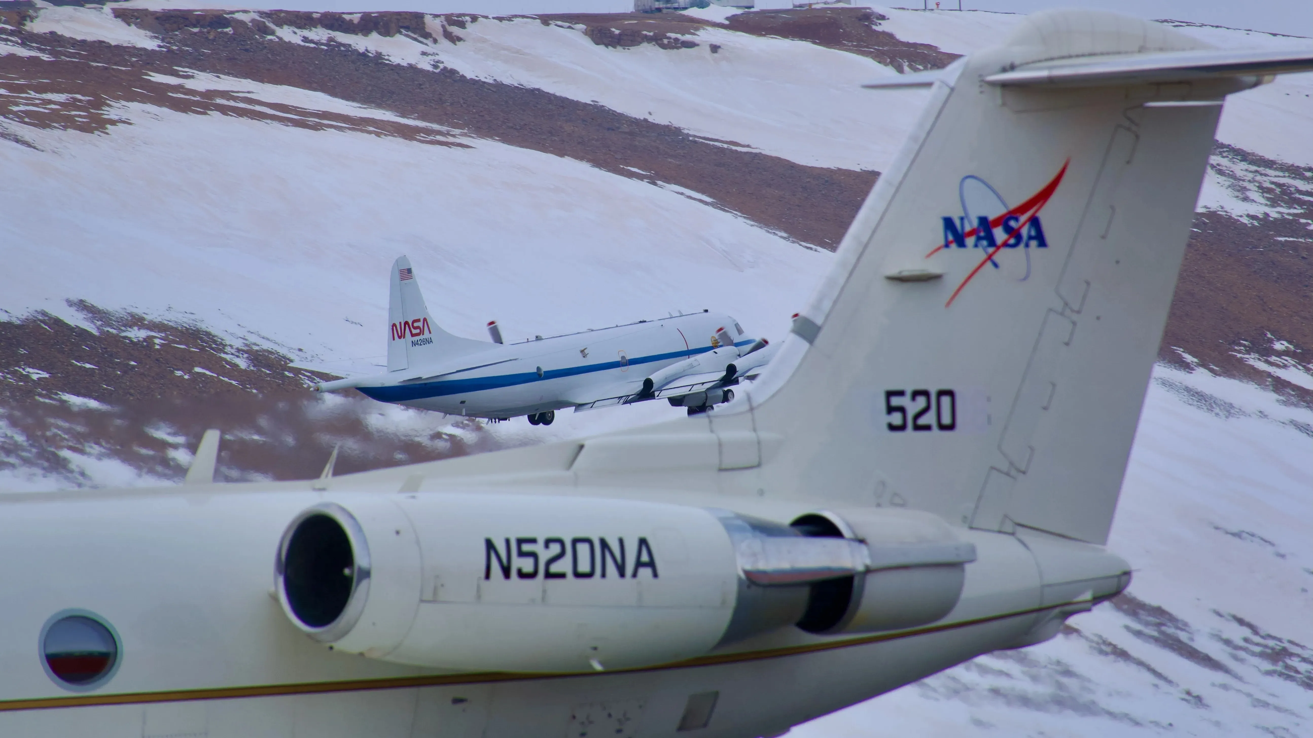 Zwei NASA-Flugzeuge über einer weißen Landschaft.