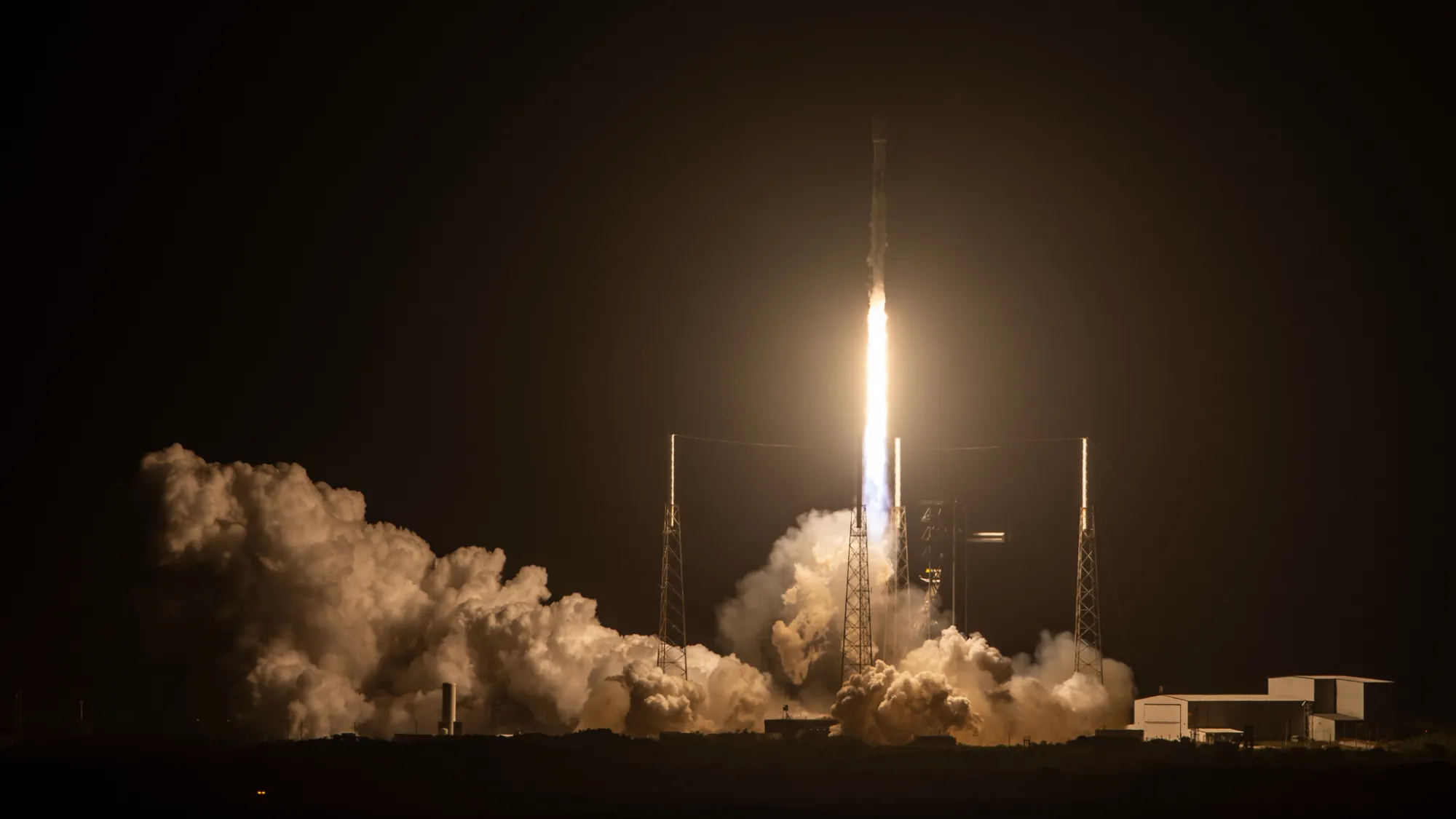 eine schwarz-weiße Rakete startet in einen dunklen Nachthimmel